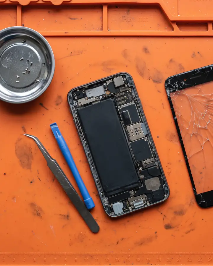 Overhead close-up of an opened phone on an anti-static mat with tiny screws in a tray. Sample photo.